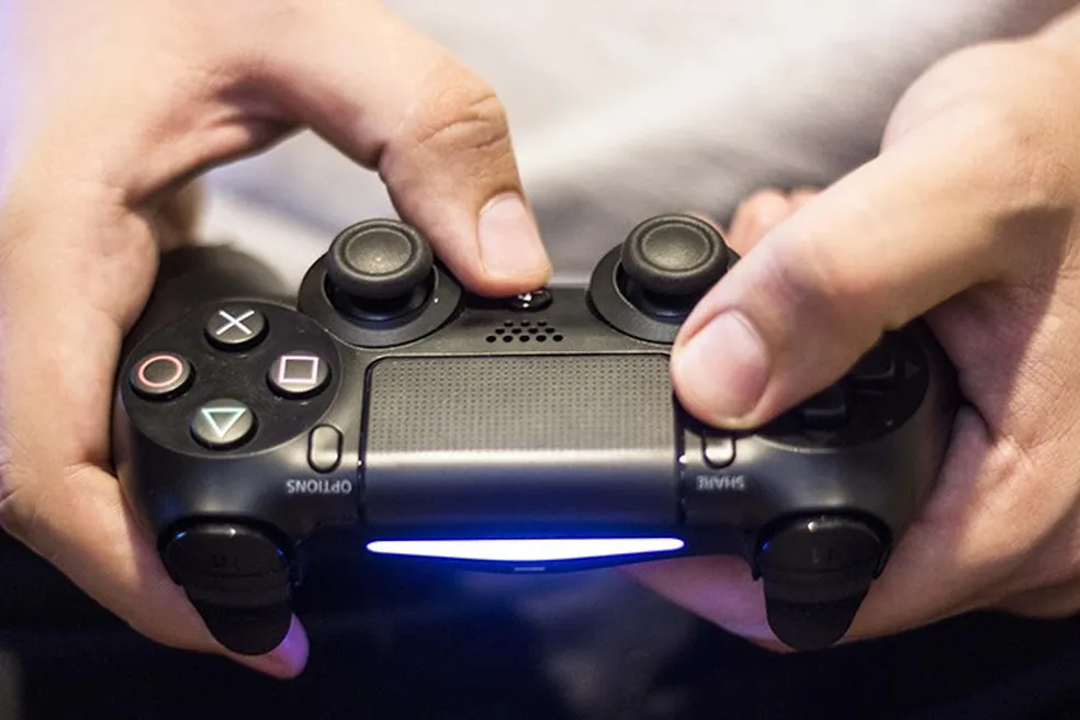 Pessoa com controle de PS4 em mãos